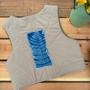 Gray quilted vest with a blue pattern on a wooden surface