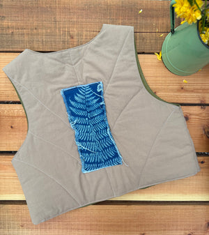 Gray quilted vest with a blue pattern on a wooden surface