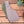 Brown and green quilted vest  on a wooden surface with flowers in a pot in the background