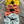 Three fabric scrunchies in yellow, orange, and blue on a wooden surface