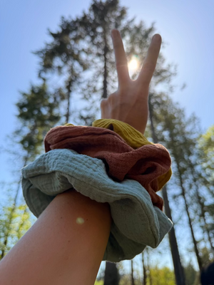 Hand making a peace sign with colourful scrunchies on wrist 