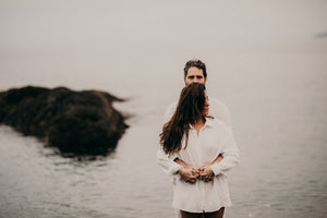 Couple standing with ocean behind them