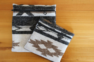 May include: Two zippered pouches with a black, white and brown geometric pattern. The larger pouch is on the bottom and the smaller pouch is on top.